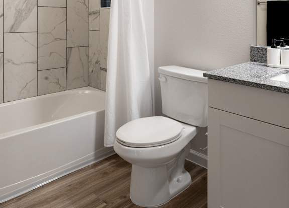 A white toilet sits next to a bathtub in a bathroom.