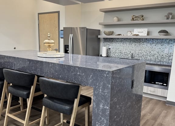A kitchen with a marble countertop and bar stools.
