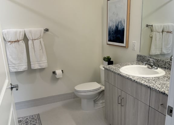 A bathroom with a toilet, sink, and towels.