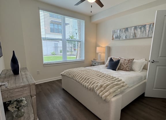 A bedroom with a bed, a ceiling fan, and a window with blinds.