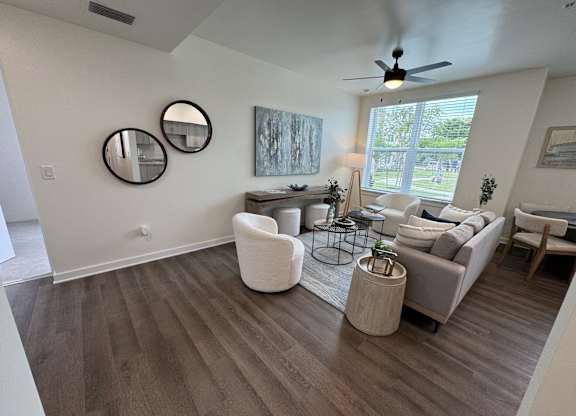 A living room with a ceiling fan and a large window.