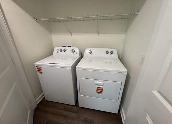 Two white front loading washing machines in a small laundry room.