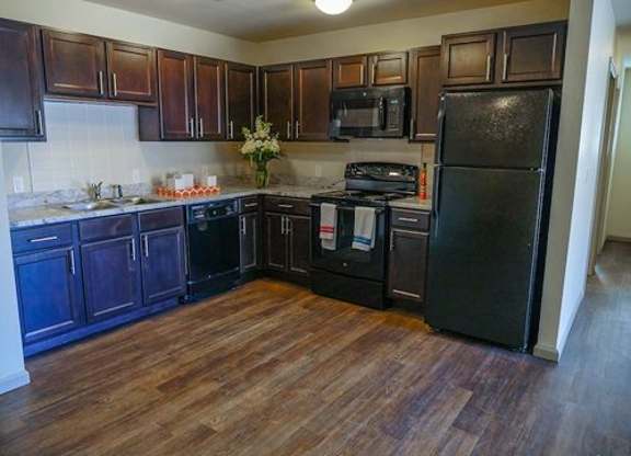 A kitchen with dark wood cabinets and a black fridge.