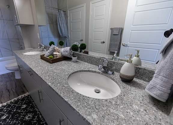 A bathroom with a white sink and a grey counter top.