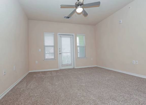 A room with a ceiling fan and carpeted floor.