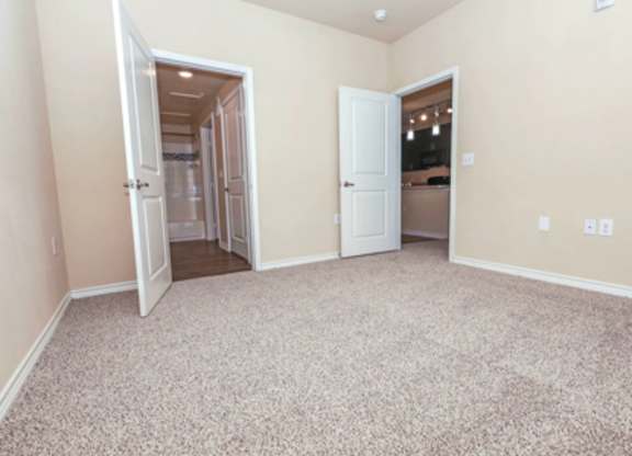 A room with a carpeted floor and two open doors.