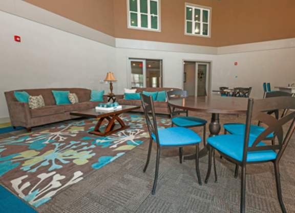 A living room with a brown couch, blue chairs, and a patterned rug.