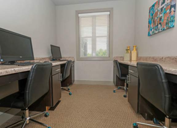 A room with a desk and chairs and a window.