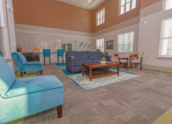A living room with a blue couch and a grey rug.