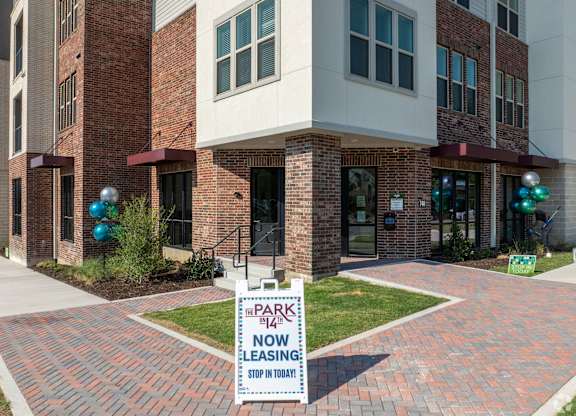 A brick building with a sign that says "Park 142 No Leasing Stop In Today".