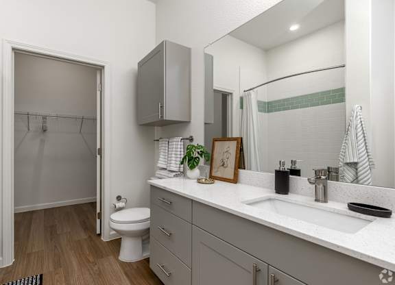 A bathroom with a white toilet, sink, and a mirror.
