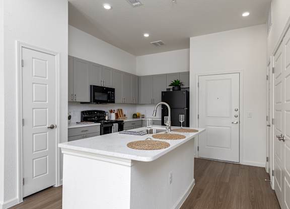 A kitchen with white cabinets and a white island with a sink.