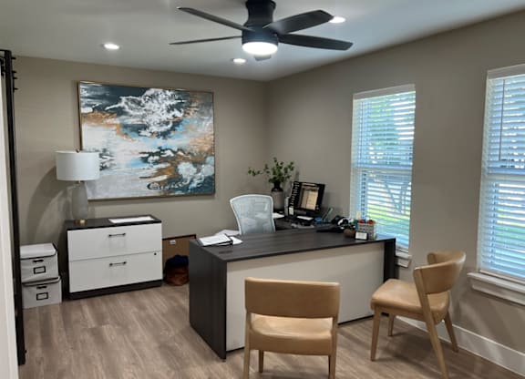 A room with a desk, chair, and painting on the wall.