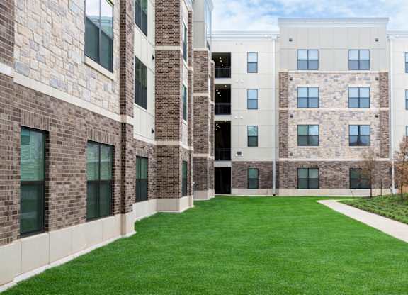 A grassy courtyard is surrounded by a brick building.