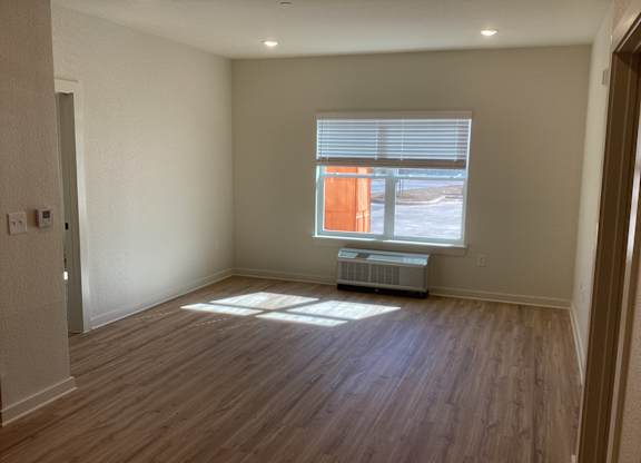 A room with wooden floors and a window with blinds.