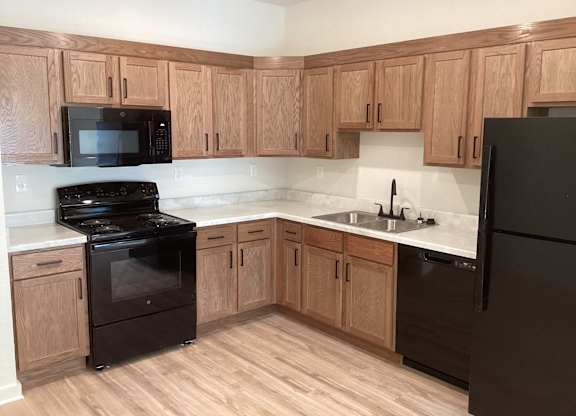 A kitchen with wooden cabinets and black appliances.