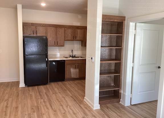 A kitchen with a black fridge and wooden cabinets.