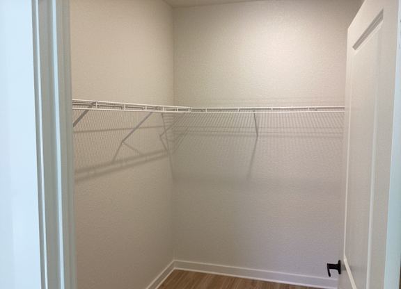 A white closet with a wooden floor and a white door.