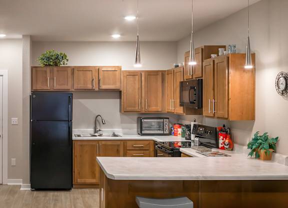 A kitchen with wooden cabinets and a black refrigerator.