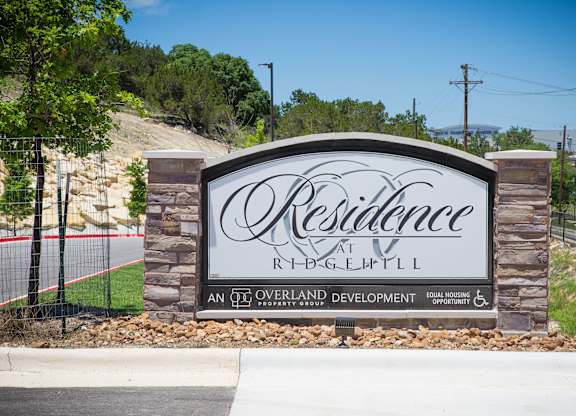 A sign for Resilience at Ridgepoint, an overland development, is displayed in front of a hill.