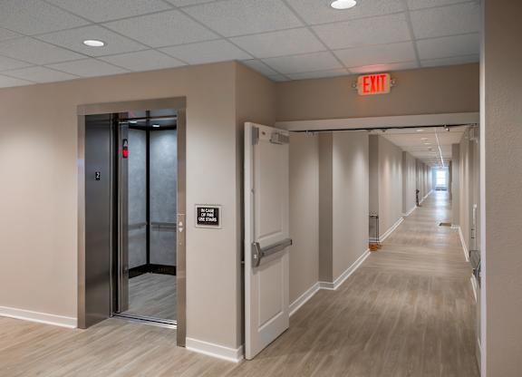 A hallway with a red exit sign above the door.