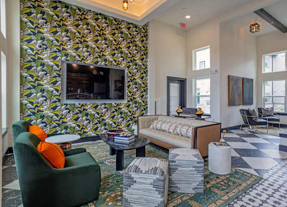 A living room with a green armchair and a patterned wallpaper.
