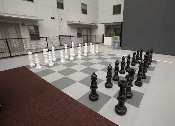 A giant chess set is set up on a checkered floor.
