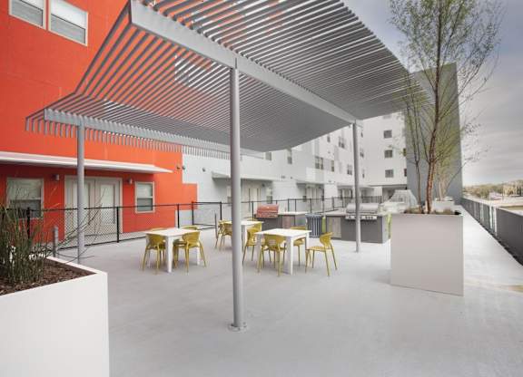 A patio with tables and chairs and a white wall.