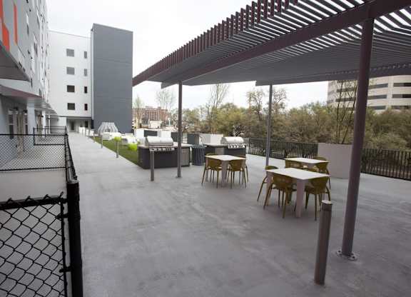 A patio with tables and chairs is covered by a roof.