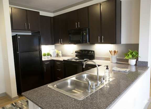A kitchen with black cabinets and a granite countertop.