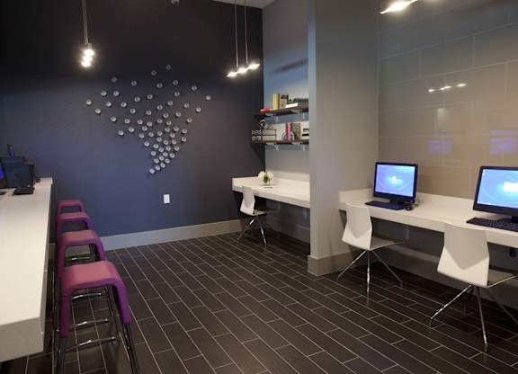 A room with a white desk and purple chairs.