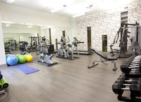 A gym with a variety of equipment including weights and exercise balls.