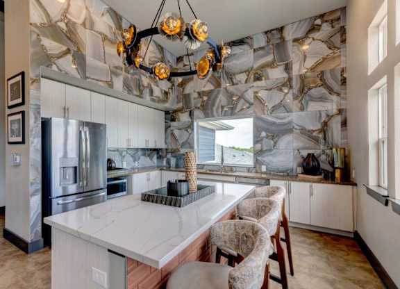 A kitchen with a marble backsplash and a large island.