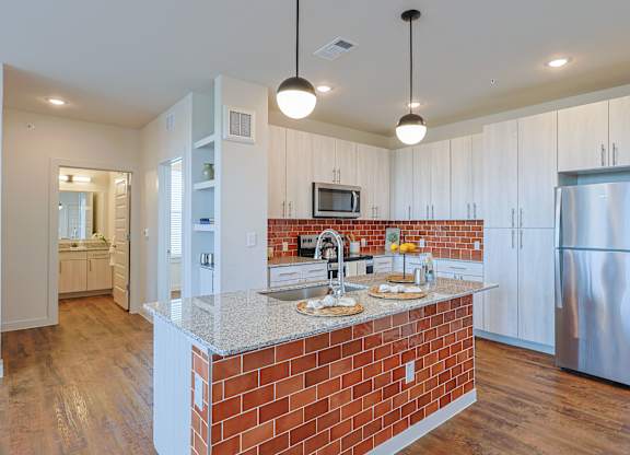 A kitchen with a brick island and stainless steel appliances.