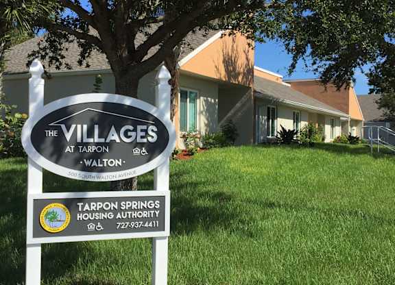 A sign for The Villages at Tarpon Walton in front of a house.