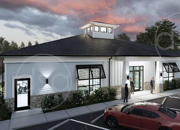 A red car is parked in front of a white building with a black roof.
