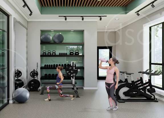 A woman is drinking water in a gym with a variety of equipment.
