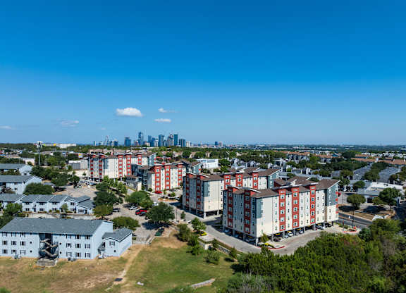 A view of a residential area with apartment buildings and a city skyline in the distance.
