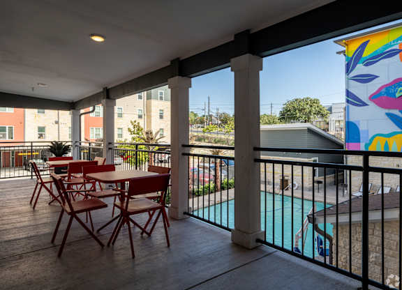 A balcony with a table and chairs overlooking a pool.