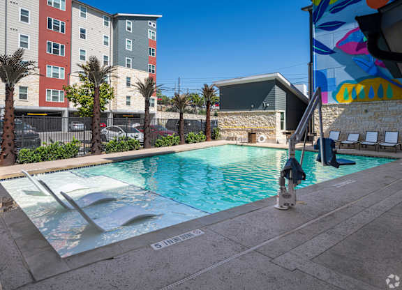 A pool surrounded by palm trees and buildings.