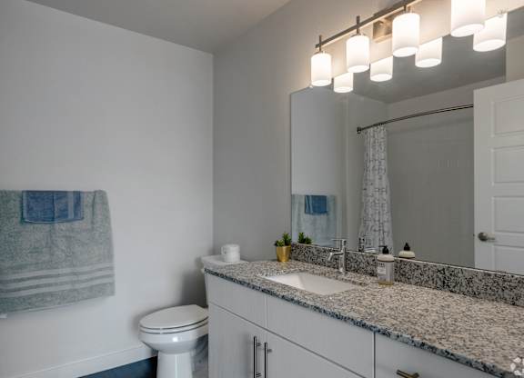 A bathroom with a toilet, sink, and mirror.