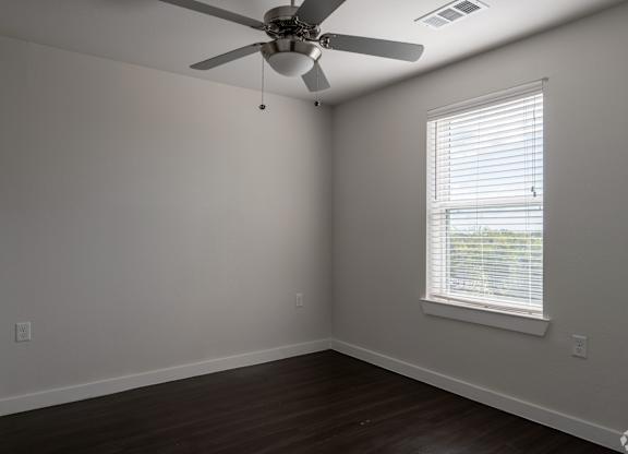 A room with a ceiling fan and a window with blinds.
