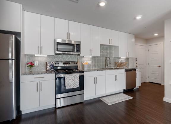 A modern kitchen with white cabinets and stainless steel appliances.