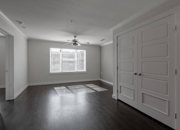 A room with a ceiling fan and a window with blinds.