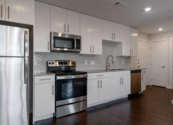 A modern kitchen with white cabinets and stainless steel appliances.