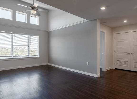 A room with a ceiling fan and wooden flooring.