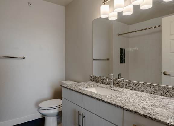 A bathroom with a toilet, sink, and mirror.