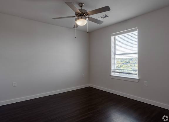 A room with a ceiling fan and a window with blinds.