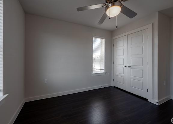 A room with a ceiling fan and a door.