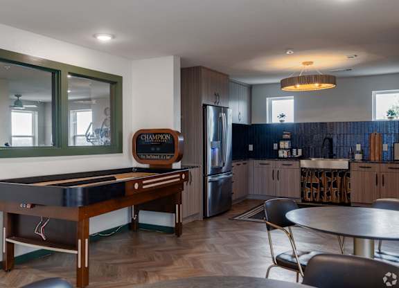 A pool table in a room with a fridge and a bar.